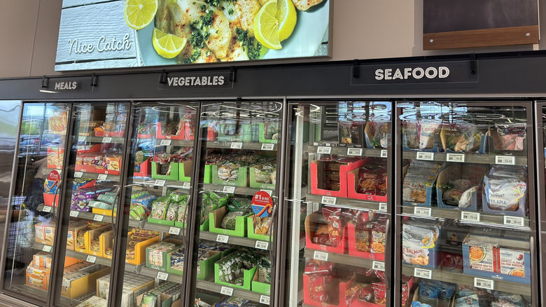 An Aldi frozen food aisle with signs for meals, vegetables, and seafood.