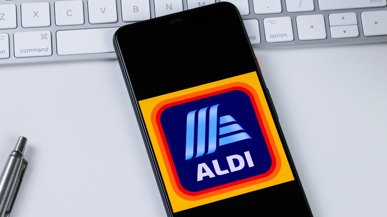Smartphone with Aldi app open over a computer keyboard.