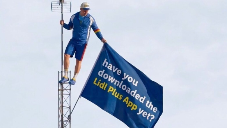 A man on pole with Lidl flag advertising the Lidl Plus app