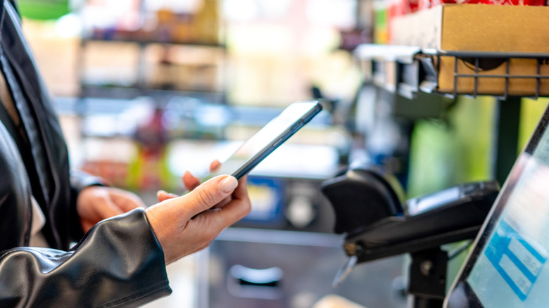 Woman using self-checkout with phone