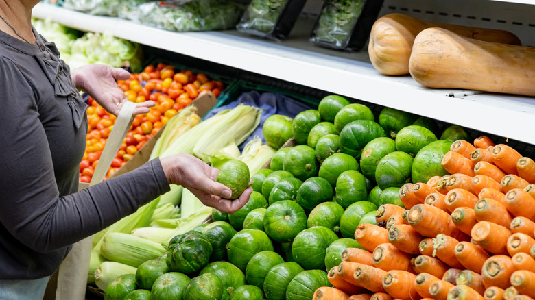 A woman shopping at the grocery store standing in the produce aisle