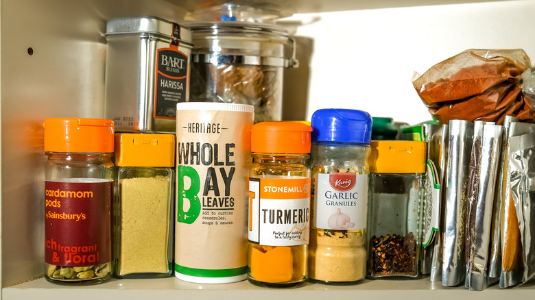 A variety of spice containers in open cabinet