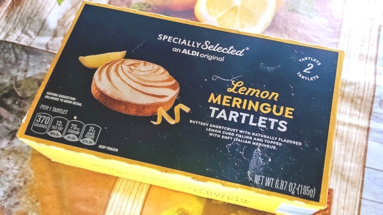box of Specially Selected Lemon Meringue Tartlets on a kitchen table covered with a lemon-patterned tablecloth