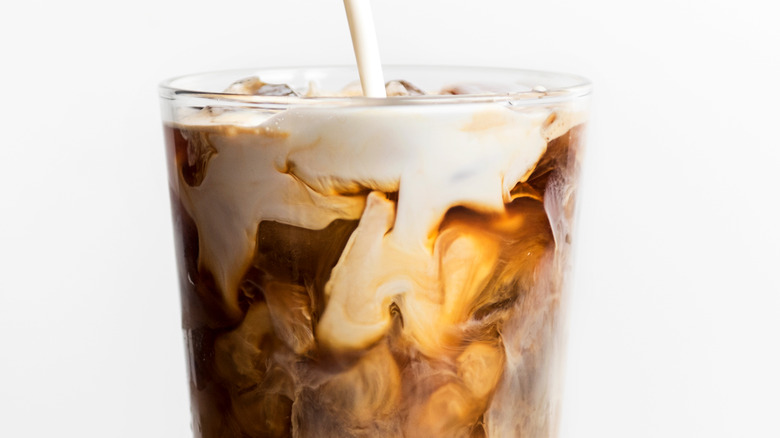 Cream poured into a glass of iced coffee