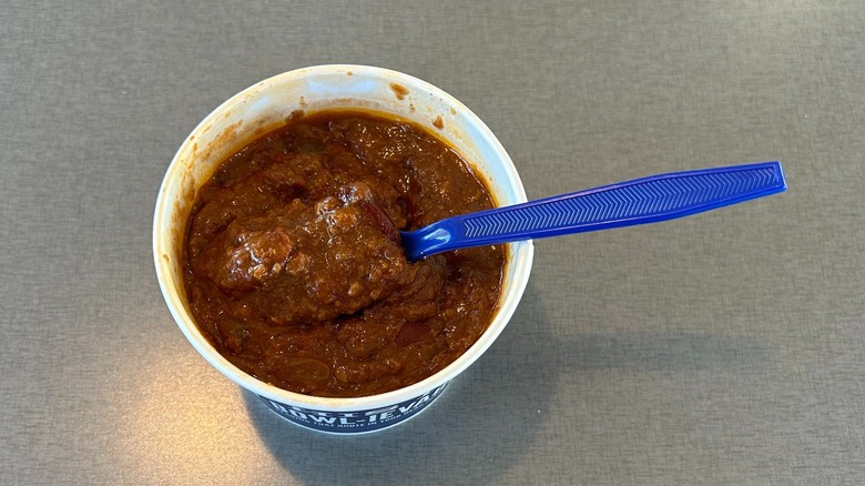 Container of chili from Culver's with a blue plastic spoon in it