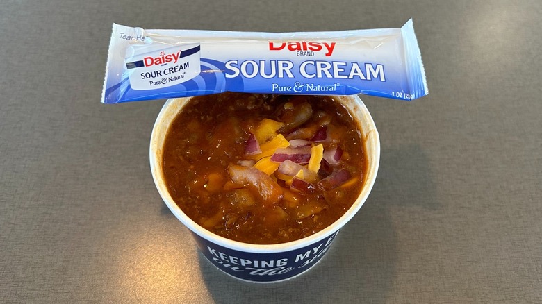 Container of chili supreme with a package of Daisy Sour Cream