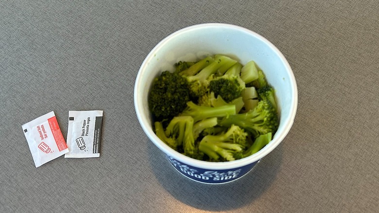 Container of steamed broccoli from Culver's with a packet of salt and pepper on the side