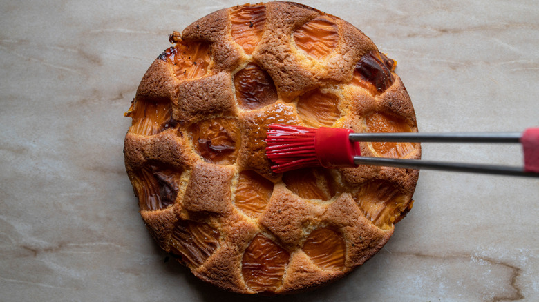 A cake being brushed with apricot glaze