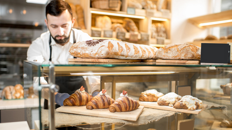 A baker placing fresh croissants inside a display case