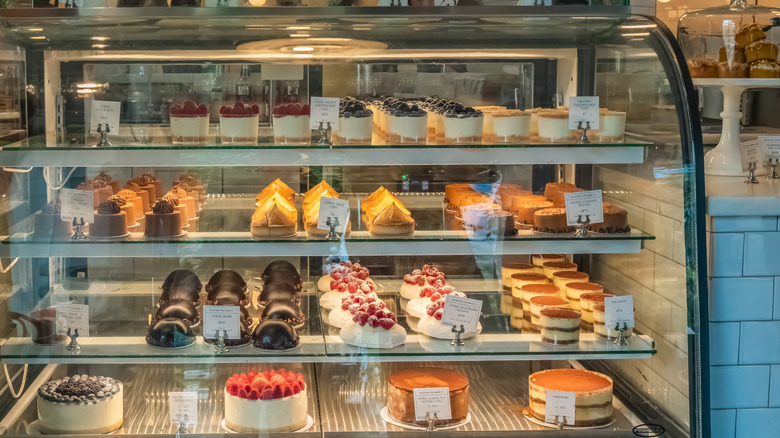Assorted cakes and desserts lined up inside a display case at a bakery