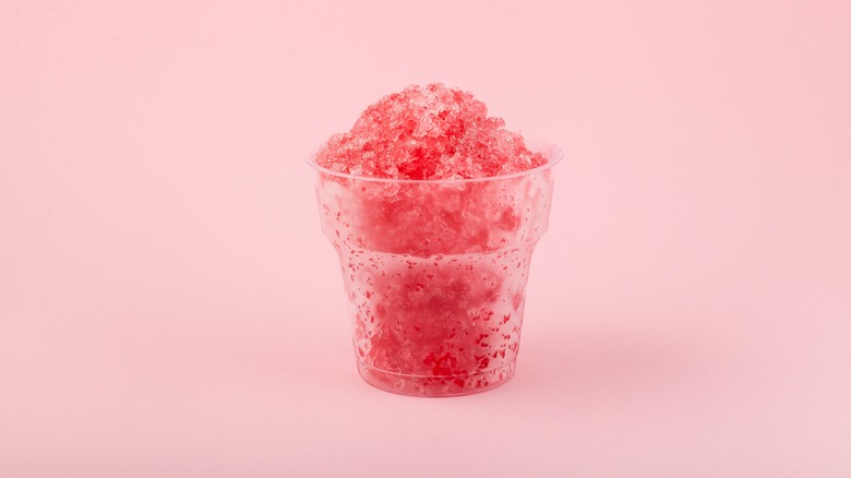 Strawberry shaved ice in a plastic cup pink background