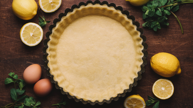 Pastry in fluted dish with lemons, eggs, and herbs