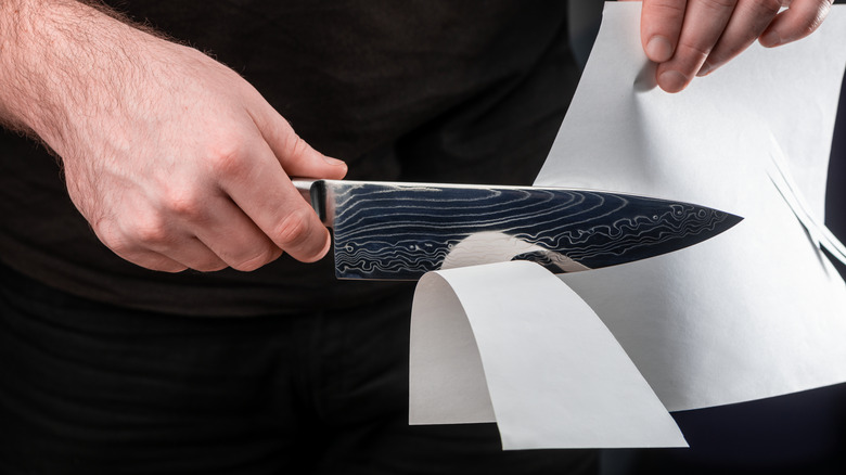 Person cutting paper with knife