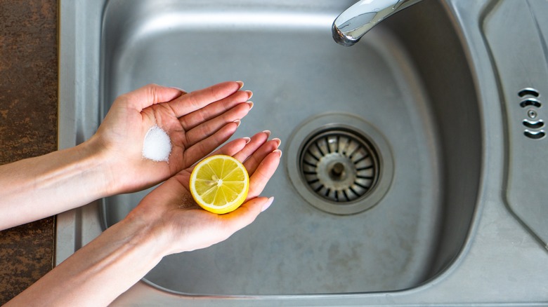 hands holding lemon and salt over sink