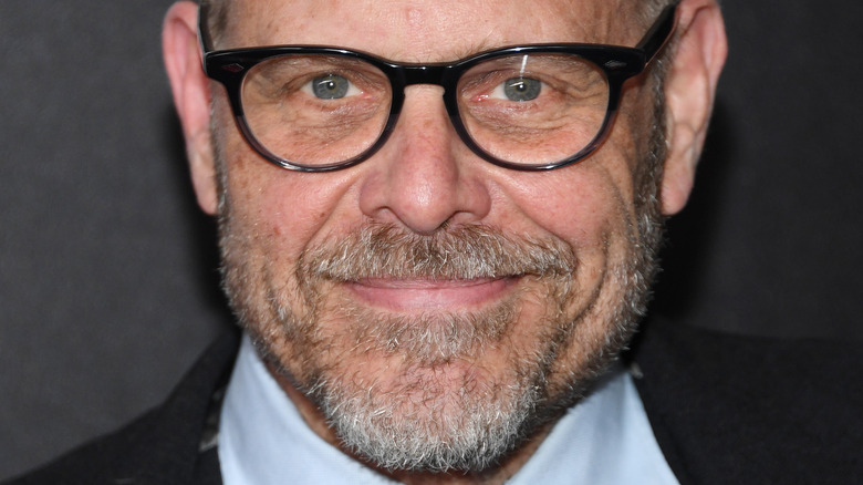 Alton Brown smiling in glasses and wearing suit