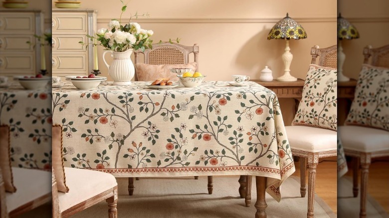 Floral tablecloth on table with chairs, flowers, bowls, and cups