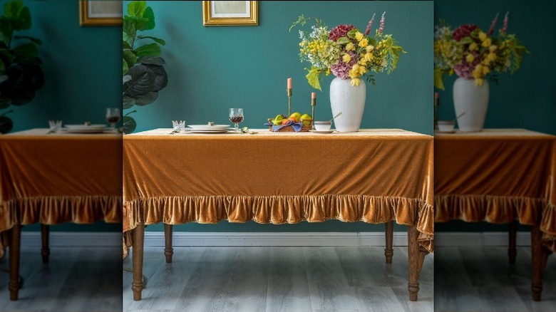 Orange velvet tablecloth on a table with flowers, candles, and place settings