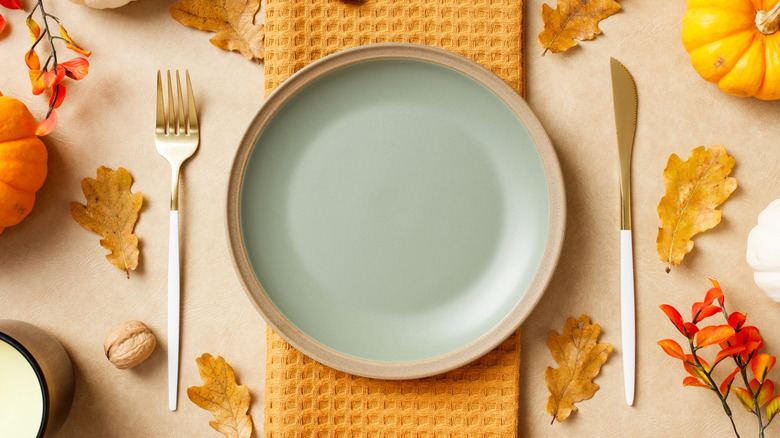 Fall themed generic table setting with a plate and silverware sitting on a placemat and table cloth