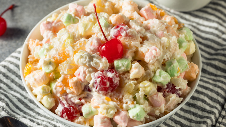 An ambrosia salad topped with a single maraschino cherry