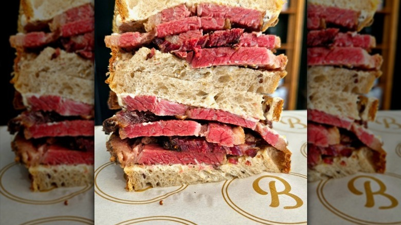 A pastrami sandwich with thick-sliced meat cut in half and the two halves are stacked on top of each other