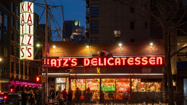 Exterior view of Katz's Delicatessen at night, with a line out the door