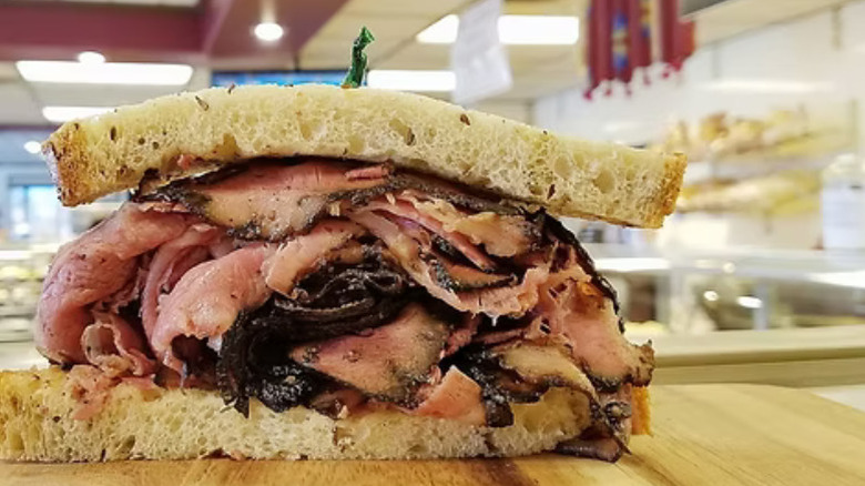 Half of a pastrami sandwich on a wooden board in The Bagel Cafe