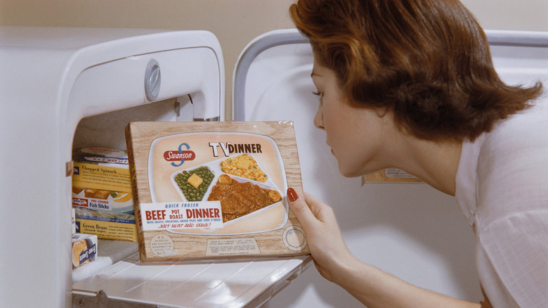 A woman pulls a Swanson TV dinner from an old-fashioned fridge