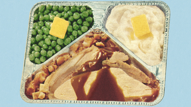 A vintage stylization of turkey with gravy, stuffing, peas, mashed potatoes in an aluminum tray