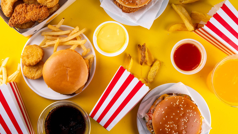 A top-down view of many staple fast food items on a yellow surface