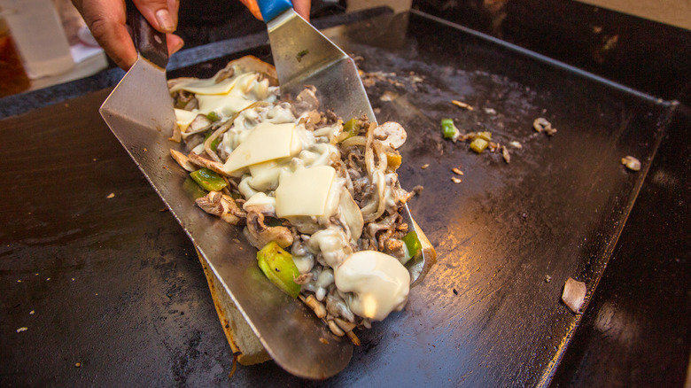 Cook making cheeseteak on a griddle