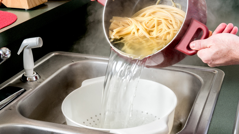 Person draining pasta in a colander