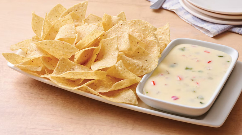 Applebee's White Queso and Chips on a white plate against a wooden table