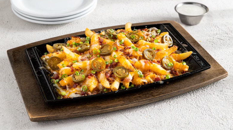 Chili's Texas Cheese Fries in a black skillet on a wooden cutting board