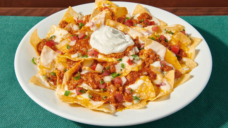Denny's Zesty Nachos against a blue tablecloth and wooden table