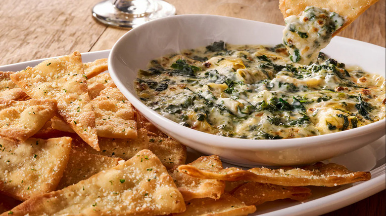 Olive Garden's Spinach-Artichoke Dip with flatbread crisps against a wooden background