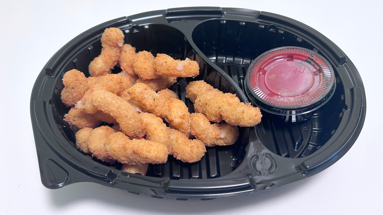 Red Robin Cheesy Mozzarella Twists and marinara sauce in a black to-go container against a white background