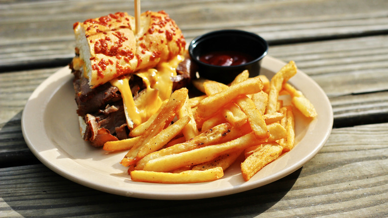 prime rib sandwich with fries on rustic table