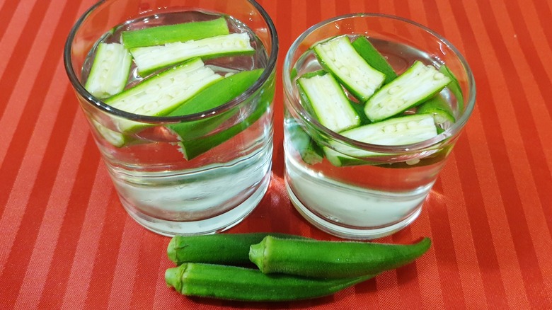 Okra floating in two glasses of water on red striped table