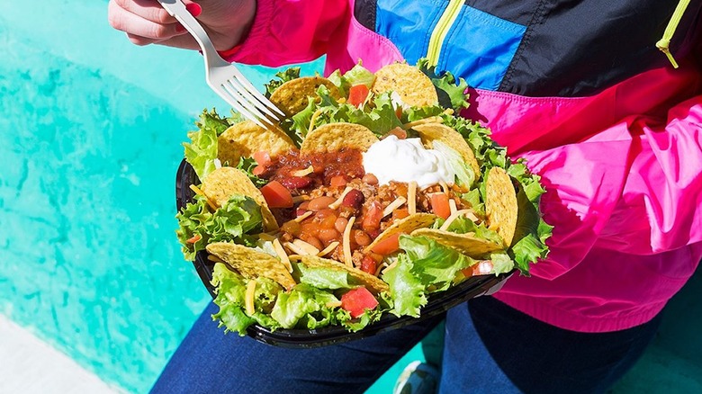 Person in bright windbreaker eats Wendy's taco salad