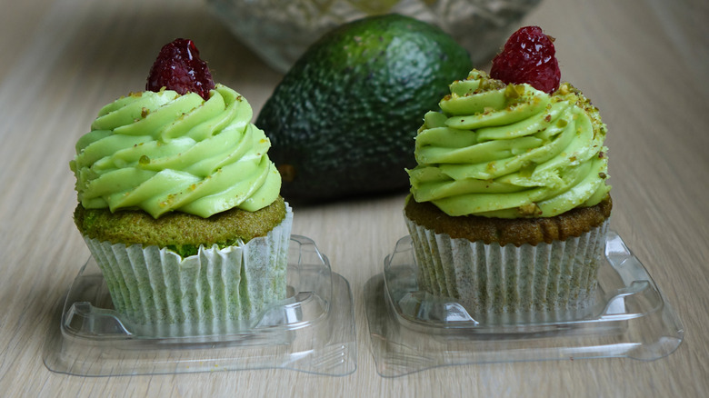 Cupcakes with avocado frosting next to avocado