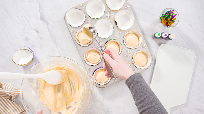 Hand scooping batter into cupcake tin