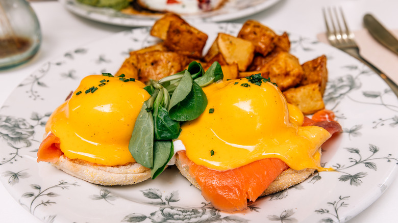 Plate of smoked salmon eggs Benedict with hollandaise sauce and fried potatoes