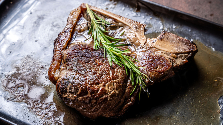 A bone in steak topped with rosemary