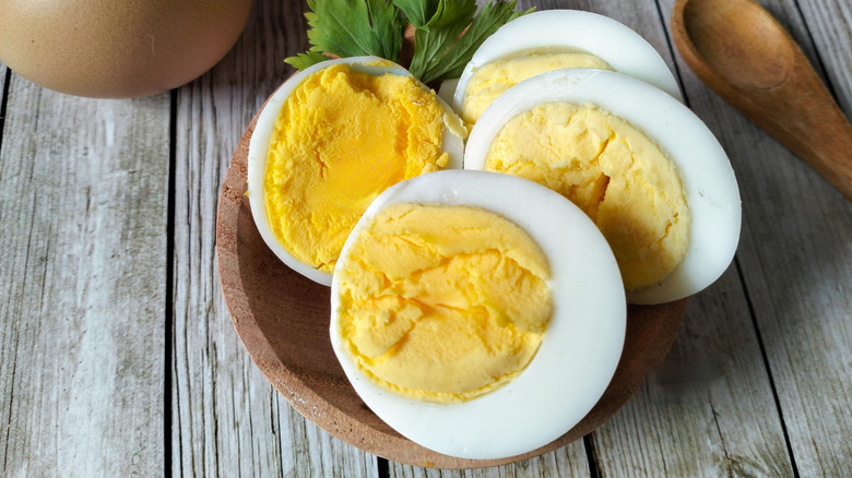 Sliced boiled eggs in rustic bowl on wooden table