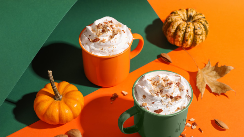 Mugs of coffee and pumpkins on a festive green and orange background