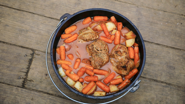 A pot roast with carrots and potatoes submerged in liquid