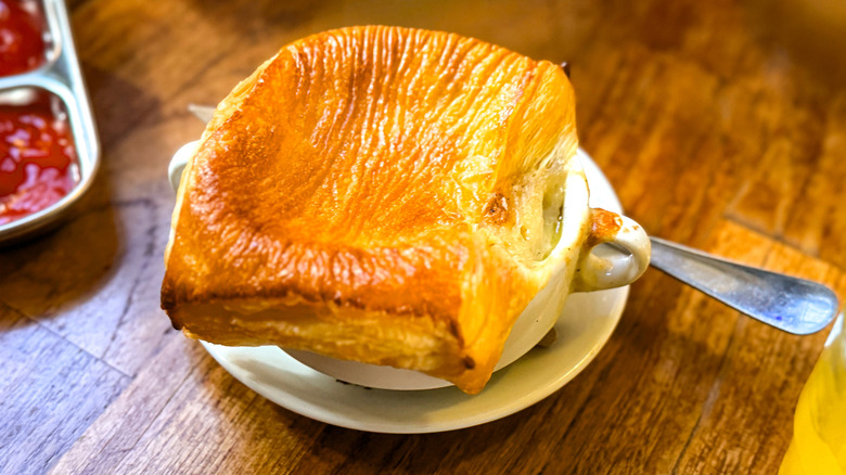 An individual pot pie in a white mug on a table