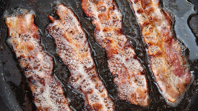 greasy bacon in frying pan