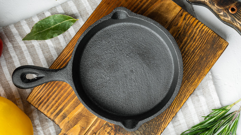 A black, cast iron skillet on a wooden cutting board