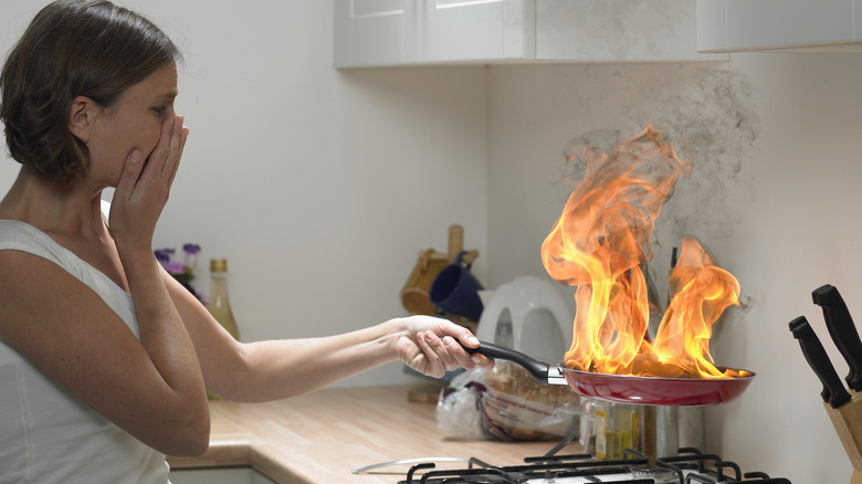 Woman holding flaming pan